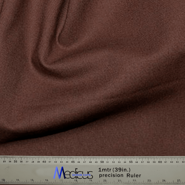 A close-up of soft, sustainable brown fabric draped in folds, paired with a precision ruler showing measurements in cm and inches—perfect for crafting the Classic Plain Brunette Brown Scrub Cap by Medicus Scrub Caps for medical professionals.
