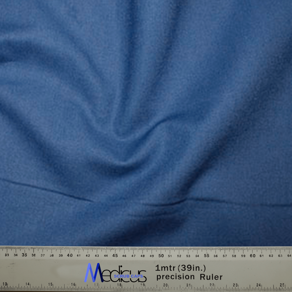 The Classic Plain Copen Blue Scrub Cap by Medicus Scrub Caps is showcased draped over a precision ruler marked 1mtr (39in.), highlighting its textured surface and gentle folds, ensuring tailored comfort in every hypoallergenic textile.