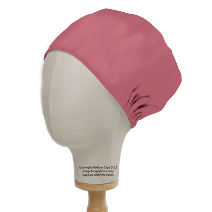 A mannequin head models a Classic Plain Coral Pink Scrub Cap by Medicus Scrub Caps against a white background, showcasing its fit and style. The image mentions the 2022 product with size and print variations for durability.