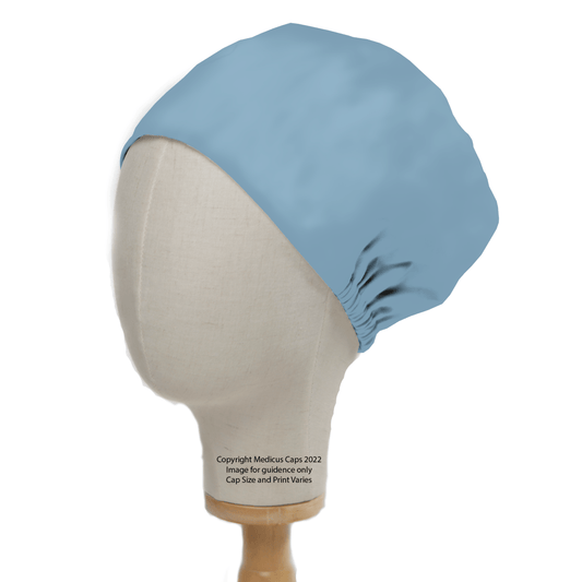 The mannequin head displays a Medicus Scrub Caps durable Classic Plain Cyan Blue Scrub Cap, featuring a smooth fabric with gathered elastic back, on a wooden stand. The image includes copyright and size disclaimer text, highlighting this essential piece of medical attire.