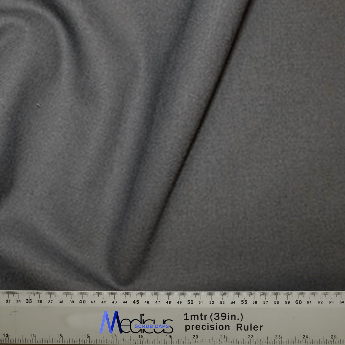 A close-up of the Classic Plain Dark Grey Scrub Cap by Medicus Scrub Caps shows a subtle crease. A ruler below displays measurements in centimeters and inches, with Media in blue and artsupply.com in black.