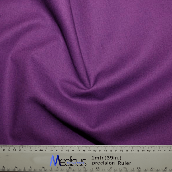 A folded Classic Plain Imperial Purple Scrub Cap by Medicus Scrub Caps is showcased, highlighting its comfort and durability, with a ruler at the bottom showing measurements in centimeters and inches.