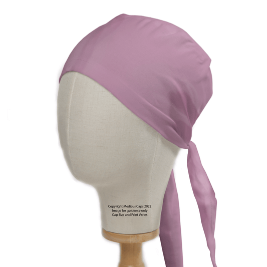 A beige mannequin head sports the Medicus Scrub Caps Classic Plain Lavender Purple Scrub Cap, a theatre hat with back ties that embodies the ideal fit for healthcare professionals. Set against a plain white background, it echoes the style of a light pink surgical cap.