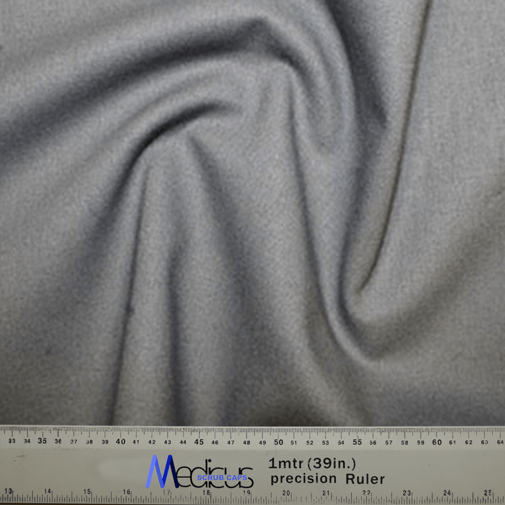 A close-up of the Classic Plain School Grey Scrub Cap fabric by Medicus Scrub Caps showcases a swirling pattern, perfect for crafting durable scrub caps. Below is a precision ruler measuring 1 meter or 39 inches, featuring both centimeters and inches for healthcare professionals precise cutting needs.