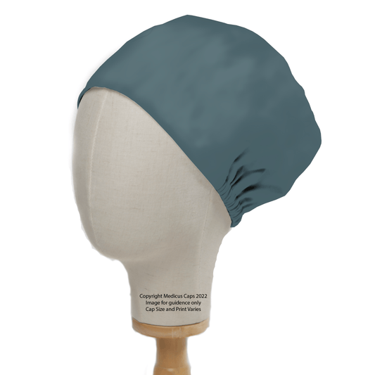 A beige mannequin head displays a Classic Plain Teal Green Scrub Cap by Medicus Scrub Caps. Made of 100% cotton, the cap covers the top and back, secured with an elastic band. The mannequin is on a wooden stand featuring copyright info and sizing notes.