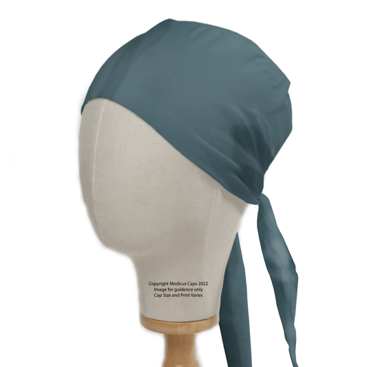 A mannequin head showcases the Medicus Scrub Caps Classic Plain Teal Green Scrub Cap, featuring a tied-back design with a long tail. Made from smooth 100% cotton fabric, it provides both comfort and durability against a white background.