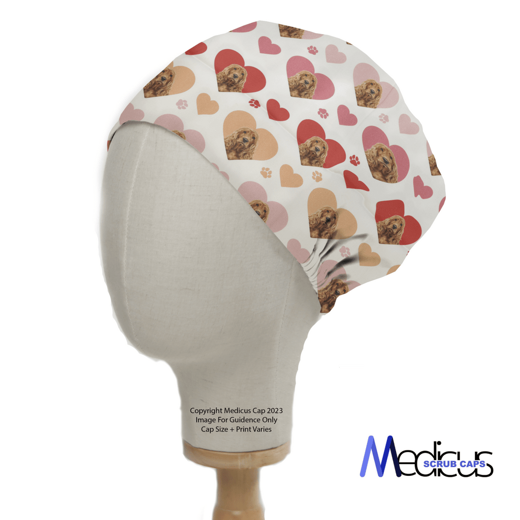 The Cocker Spaniel Dogs Hearts White Scrub Cap by Medicus Scrub Caps, perfect for healthcare professionals, is showcased on a mannequin. It features a playful red and pink heart design with dogs, including a Cocker Spaniel, on a light background and reads Copyright Medicus Cap 2023.