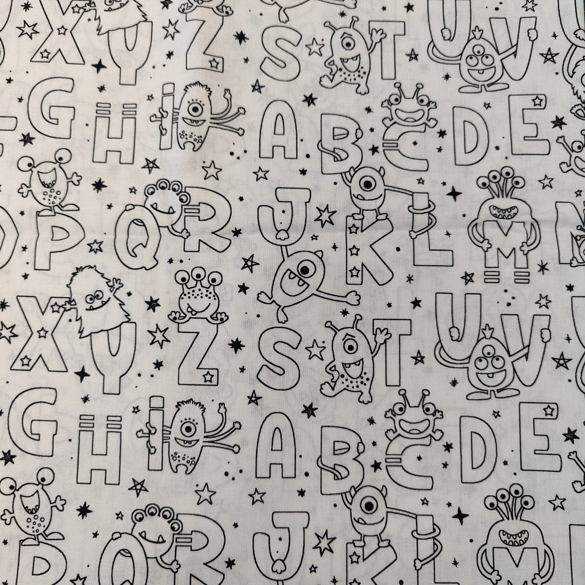 The Colour Me In Scrub Cap by Medicus Scrub Caps features a playful black-and-white pattern with cartoon aliens, monsters, and whimsical letters A-Z. Stars scatter the background, creating a fun and unique design.