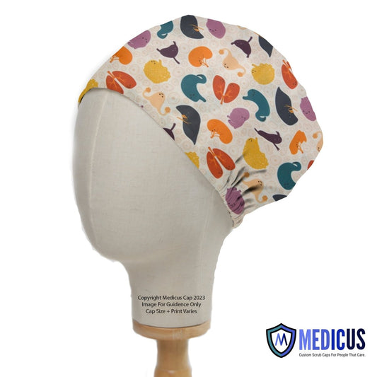 A mannequin head showcases a Medicus Scrub Caps Colourful Organs Hearts Kidneys medical cap with lively whale patterns in orange, purple, teal, and brown. Ideal for healthcare professionals, the design varies slightly in size and print and features the Medicus logo on the bottom right corner.