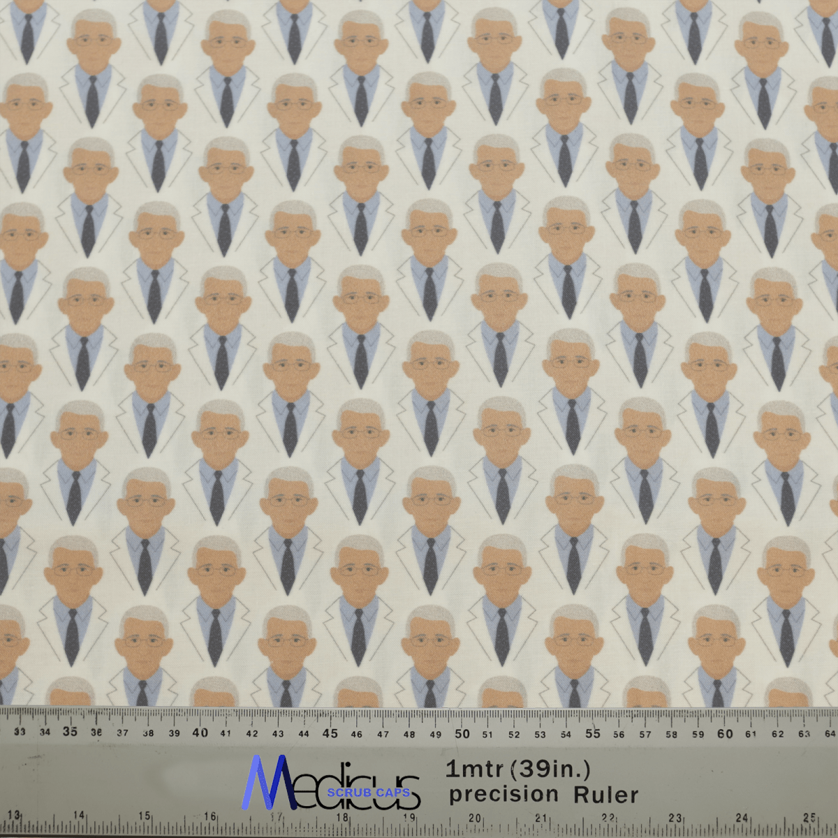 The Covid Dr Facci Doctor Scrub Cap by Medicus Scrub Caps features a repeating pattern of a professional-looking figure in a white coat. Ruler provides scale.