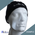 A mannequin head wears a black headwrap from Medicus Scrub Caps, showcasing a white embroidered design of a heartbeat and skyline made from premium fabric. Medicus and EXAMPLE are highlighted on green and gray sections. Perfect for custom scrub caps with personalized embroidery.