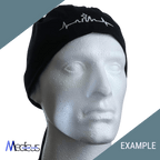 A mannequin head wears a black headwrap from Medicus Scrub Caps, showcasing a white embroidered design of a heartbeat and skyline made from premium fabric. Medicus and EXAMPLE are highlighted on green and gray sections. Perfect for custom scrub caps with personalized embroidery.