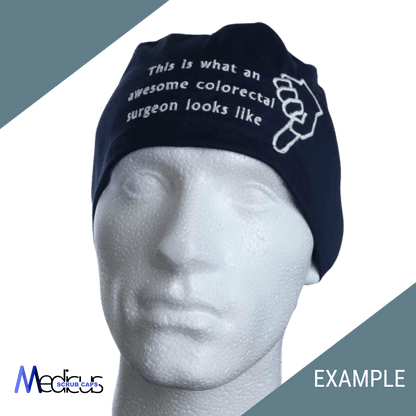 A mannequin head displays a Custom Scrub Cap by Medicus Scrub Caps featuring embroidery: This is what an awesome colorectal surgeon looks like with a hand point symbol. The background is diagonally split in light and dark green, with logos at the corners.