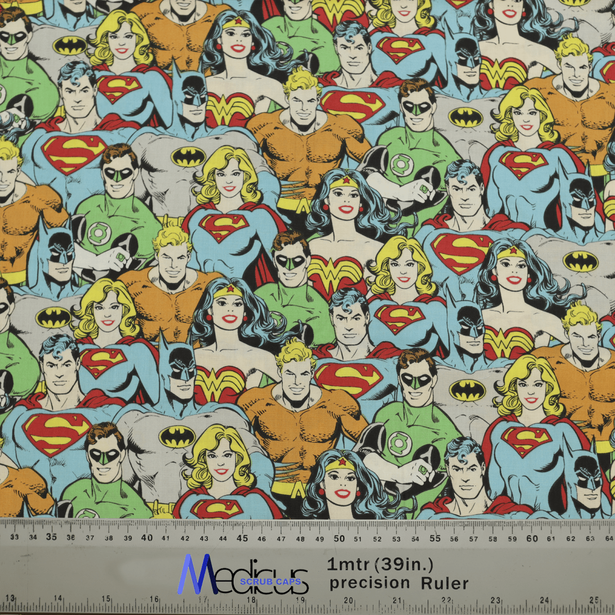 The DC Character Crowd Colourful Scrub Cap by Medicus Scrub Caps showcases a vibrant superhero pattern, featuring iconic characters in bold colors. Ruler for scale included.