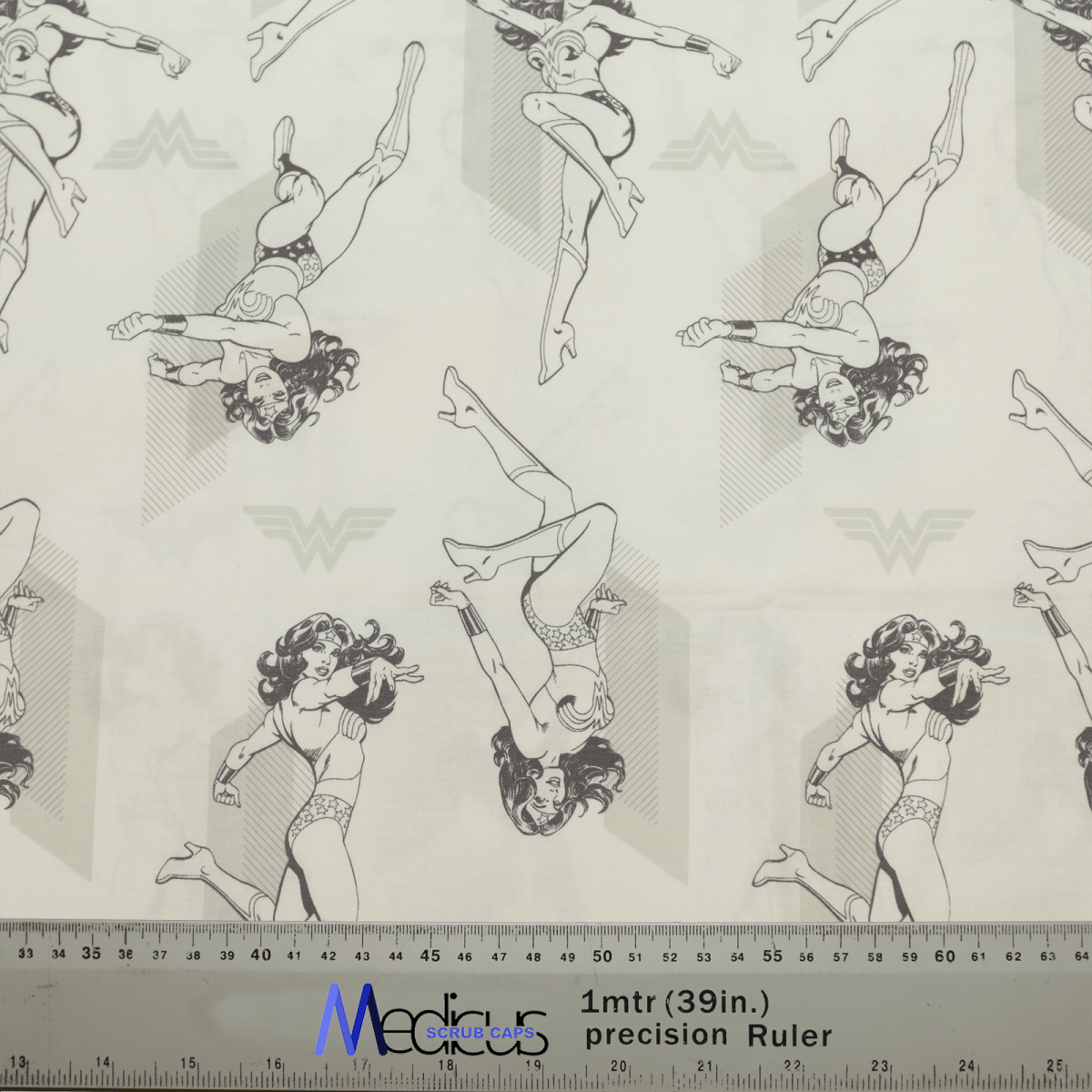 The DC Comic Wonder Woman Light Grey Monochrome Scrub Cap by Medicus Scrub Caps features patterned fabric with illustrated superhero poses. The light grey background highlights the star motifs, and a ruler at the bottom adds scale, ideal for healthcare professionals wanting a heroic look.