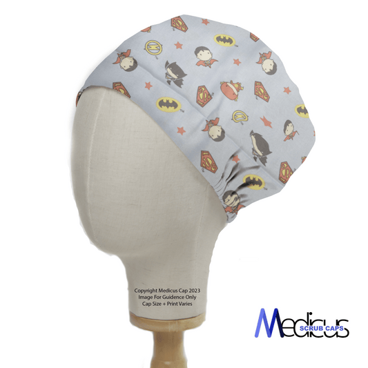 A mannequin head wears a DC Kawaii | Batman | Wonder Woman On Blue Scrub Cap with superhero motifs, branded as Medicus Scrub Caps in the bottom right corner.