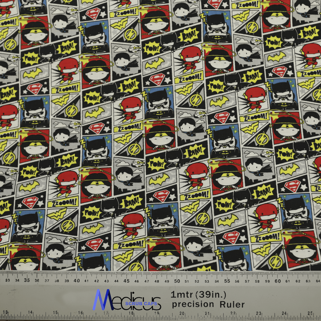 The DC Kawaii Comic Strip Scrub Cap by Medicus Scrub Caps showcases vibrant cartoon superheroes with symbols like lightning bolts and Pow! and Zoom! dialogue bubbles, plus a precision ruler at the bottom for measurements.