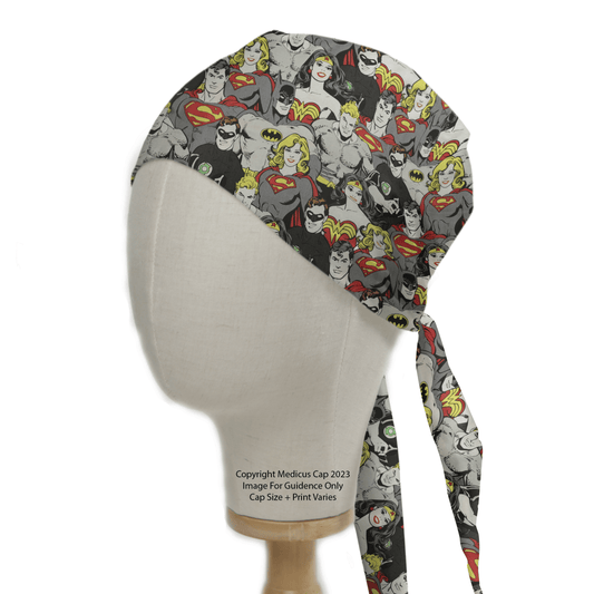 A mannequin wears the Medicus Scrub Caps DC Superheroes Monochrome scrub cap, featuring Superman and Superwoman in red, yellow, and gray. Ties at the back.