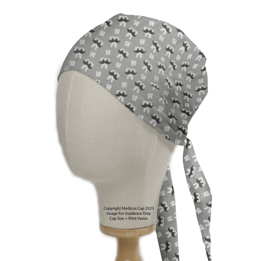 A mannequin head showcases the Dental Mr Tooth Scrub Cap from Medicus Scrub Caps, featuring a gray design with white molar teeth and black mustaches. This stylish, reusable cap ties at the back, combining functionality with charm.