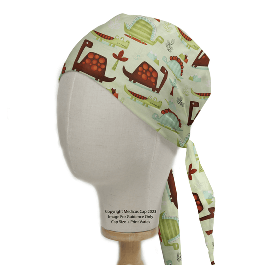 A mannequin displays the Dinosaurs in a Swamp Green Scrub Cap by Medicus Scrub Caps, featuring a playful print of red and green cartoon dinosaurs, leaves, and eggs on an eco-friendly light background.