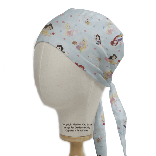 The Disney Princess on Blue Bella Snow White Scrub Cap by Medicus Scrub Caps is styled on a mannequin head with lengthy ties cascading down one side, adorned with Disney Princesses and hearts.