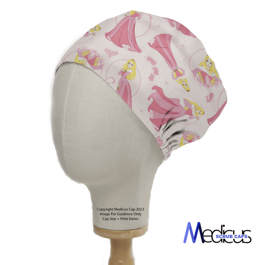 A mannequin head wears a Disney Princess Sleeping Beauty Scrub Cap featuring a princess in a pink gown, flowers, and birds on a light background. The Medicus Scrub Caps logo is in the bottom right, highlighting sustainable healthcare fashion.