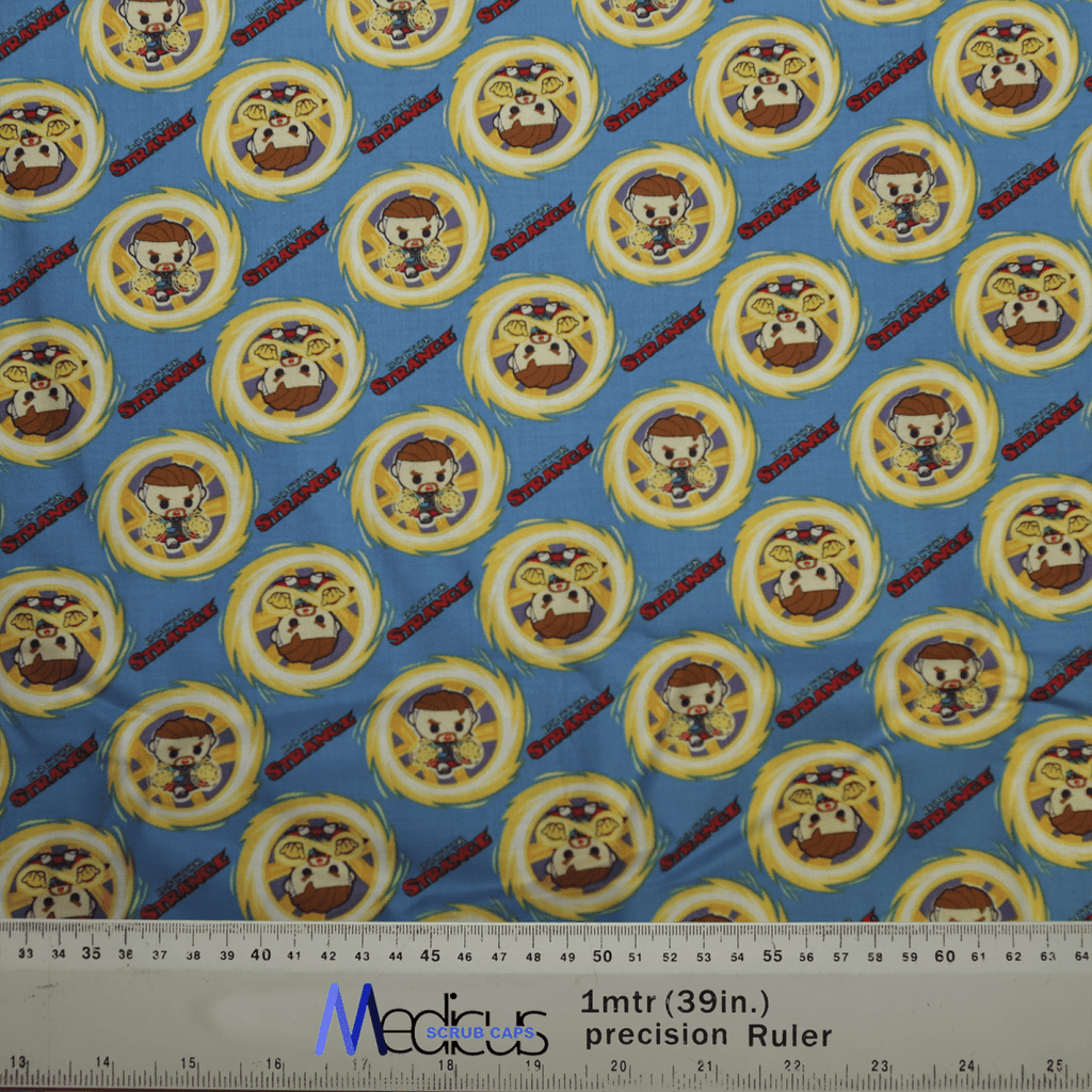 The Medicus Scrub Caps Doctor Strange Kawaii Superhero Scrub Cap exhibits cartoon characters in circular patterns on blue, with small, repeating figures of a character in a brown outfit with a distinctive hat and yellow ring. A ruler at the bottom shows size reference.
