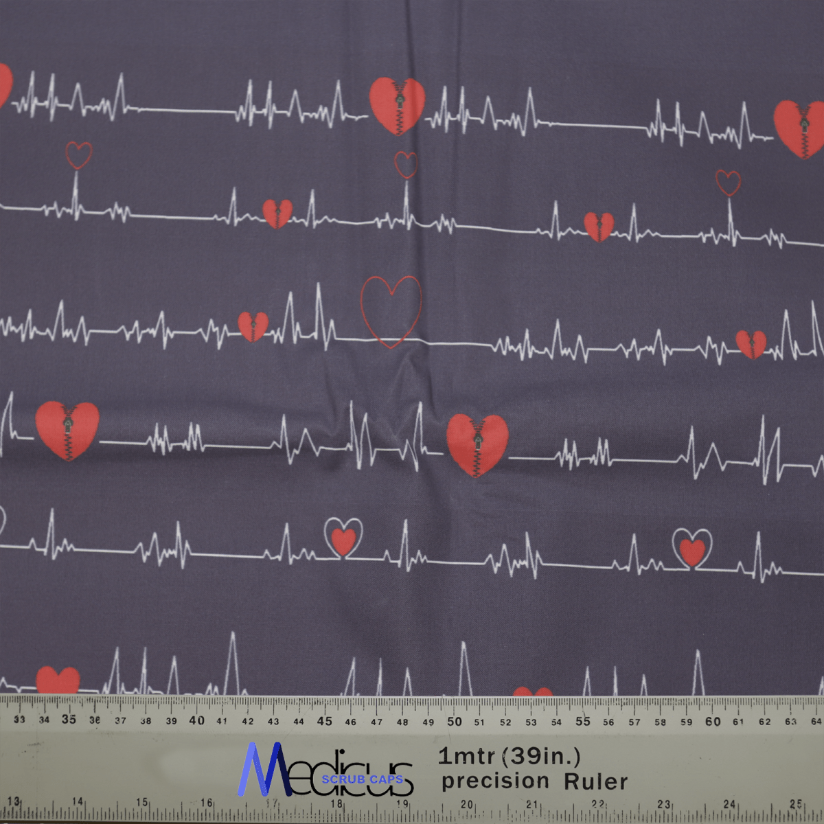 The Medicus Scrub Caps EKG Heart Monitor #2 Scrub Cap features an eco-friendly dark fabric adorned with red heart and EKG patterns, plus a ruler showing measurements in inches and centimeters.