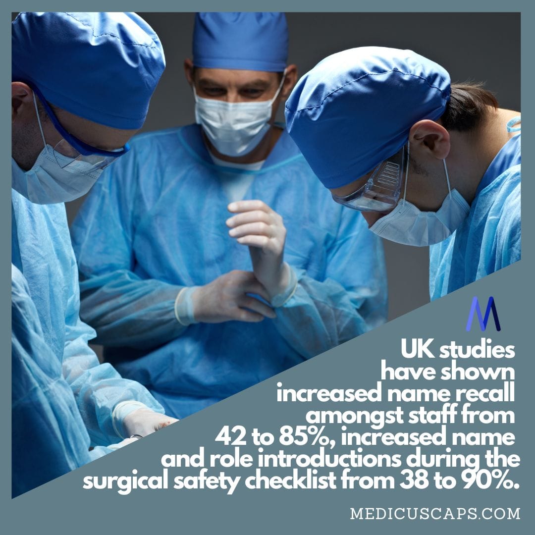 Three medical professionals in surgical attire, wearing Medicus Scrub Caps Embroidery - Baby Feet Maternity scrub caps, focus intently on an operating room task. Overlaid text highlights UK studies showing improved name and role recall among staff during surgical safety checklists.