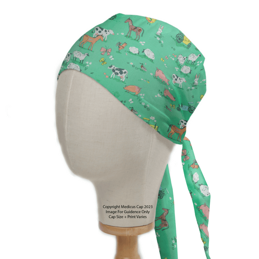 The Medicus Scrub Caps Farmers Field Scrub Cap, adorned with farm animals like cows, sheep, pigs, and goats on a green background, ensures comfort and tranquility. Featuring adjustable ties at the back and displayed on a mannequin head.