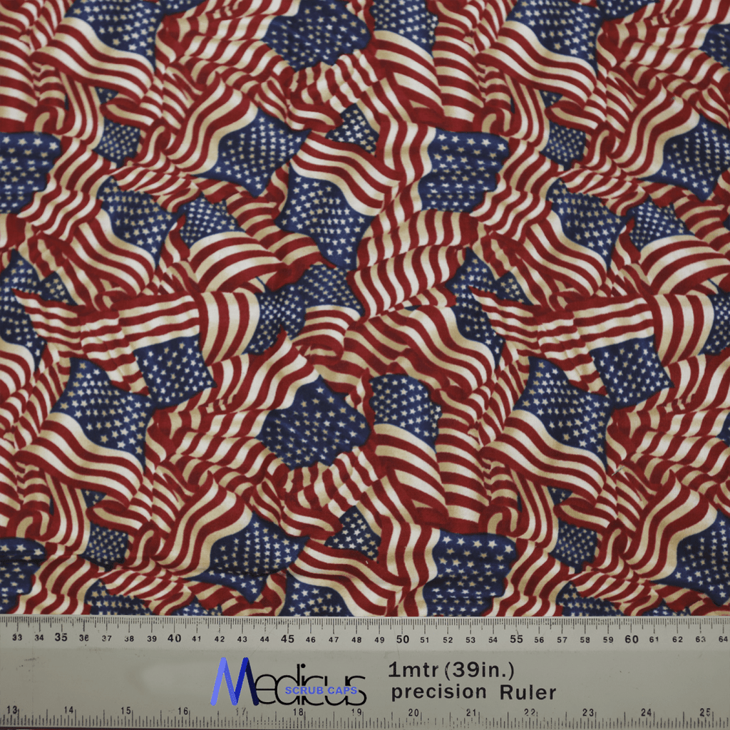 The Flag USA Scrub Cap by Medicus Scrub Caps features a vibrant pattern of overlapping U.S. flags in red, white, and blue, embodying patriotic pride. It includes a ruler at the bottom for measurements in inches and centimeters, adding practicality.
