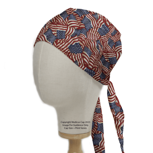 A mannequin head wears Medicus Scrub Caps Flag USA Scrub Cap, adorned with overlapping red, white, and blue American flags. Representing Patriotic Pride, it has long ties at the back for a perfect fit.