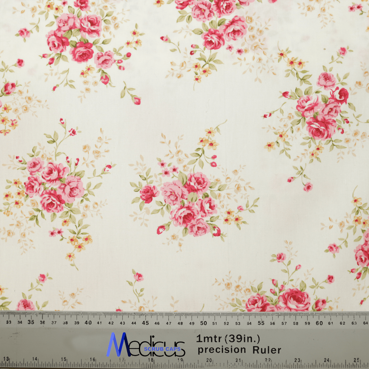 The Floral Flower Arrangement Roses White Scrub Cap by Medicus Scrub Caps features a pink rose and green leaf design on a white background, ideal for crafting sustainable scrub caps. A ruler with both inch and centimeter marks ensures precision.