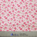 The Floral Pink On Baby Pink Scrub Cap by Medicus Scrub Caps features pink roses with green leaves on white fabric. Ideal for medical professionals, it includes a ruler at the bottom for precise measurements in centimeters and inches, blending style and functionality.