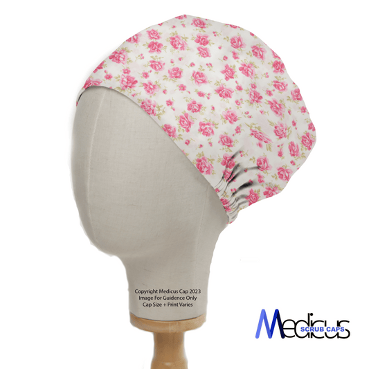 A mannequin head displays the Floral Pink On Ivory Scrub Cap by Medicus Scrub Caps, featuring a pink floral rose design. The logo Medicus Scrub Caps at the bottom right emphasizes their commitment to sustainable healthcare.