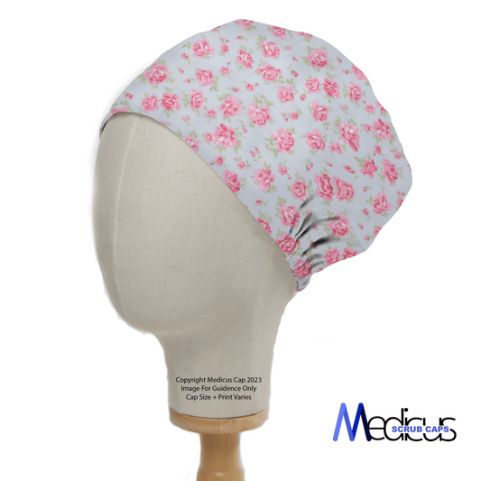 The mannequin displays the eco-friendly Medicus Scrub Caps Floral Roses Small On Blue Scrub Cap, featuring a pink and green rose pattern on white, showcased in profile with subtle branding.