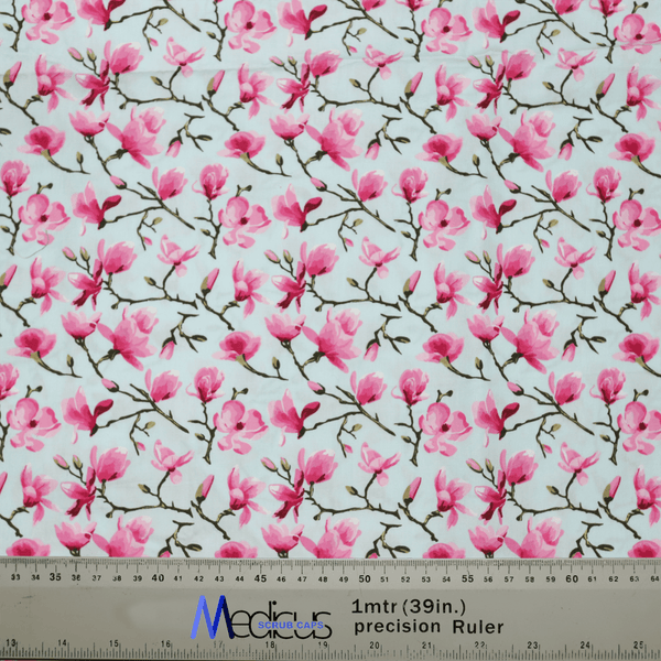 The Floral Tree Blossom Scrub Cap by Medicus Scrub Caps features pink magnolia flowers and branches on a light background, perfect for healthcare professionals. Displayed with a ruler at the bottom, it shows measurements in inches and centimeters.