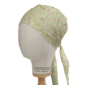 A mannequin head displays the Medicus Scrub Caps Floral Vintage Faded Green Scrub Cap, featuring pink and white blooms. Elegantly tied at the back, it has a soft, silky texture perfect for healthcare professionals who prioritize style and comfort.