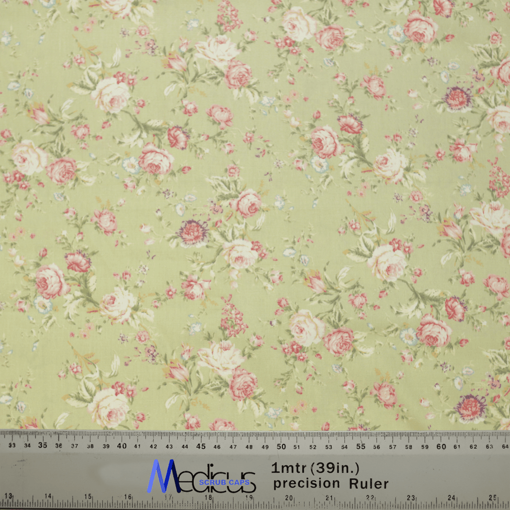 The Floral Vintage Faded Green Scrub Cap by Medicus Scrub Caps showcases pink and red roses, small white flowers, and green leaves on a pale green background. Perfect for healthcare professionals, it includes a ruler at the bottom with centimeters and inches for scale.