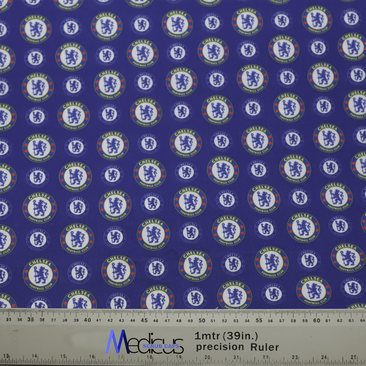 A blue fabric with repeated Chelsea football club logos mimics a Medicus Scrub Caps Football Club Chelsea Scrub Cap. A ruler at the bottom in cm and inches ensures compliance with design standards.