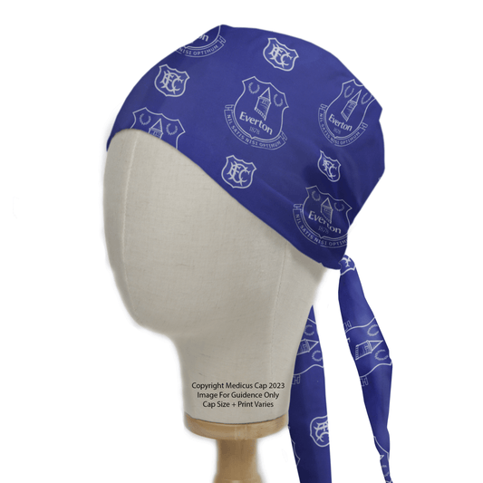 The Medicus Scrub Caps Football Club Everton Scrub Cap, featuring white club logos on a blue eco-friendly fabric, is displayed on a mannequin head with side and front views. Ties drape to the side, and text offers copyright info and guidance for this inclusive sizing option.