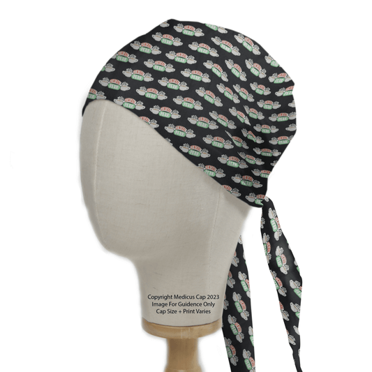 The mannequin head displays the Friends Central Perk Scrub Cap by Medicus Scrub Caps, featuring tiny ambulances and red dots on black. This sustainable cap ties stylishly at the back, adding a playful touch reminiscent of Friends Central Perk.