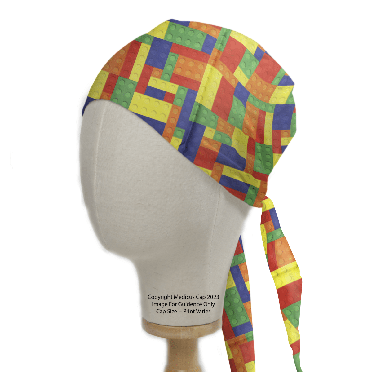 The Medicus Scrub Caps Games Lego Tetris Large Scrub Cap features an eco-friendly design with vibrant interlocking bricks in red, blue, yellow, green, and orange. Adjustable ties at the back ensure a perfect fit, as showcased on a mannequin head.