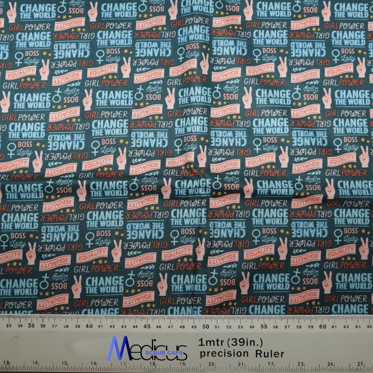 The Medicus Scrub Caps Girl Power Change The World fabric swatch features vibrant slogans like GIRL POWER, CHANGE THE WORLD, and GIRL BOSS. Its ideal for a unique scrub cap, with a backdrop of stars and peace signs, plus a measuring ruler at the bottom for fabric length.