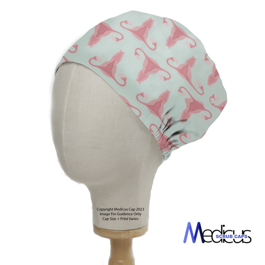 A Medicus Scrub Caps mannequin head models the Gynecology Surgeon Scrub Cap, showcasing pink uteruses on a light blue background—perfect for gynecology surgeons desiring a stylish and reusable accessory.