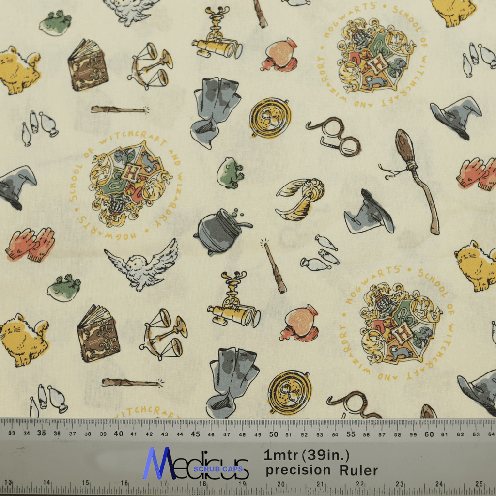 Medicus Scrub Caps Harry Potter Crest Cauldron Wand on Beige fabric with magical illustrations, including owls, books, and broomsticks. A ruler measures length below.