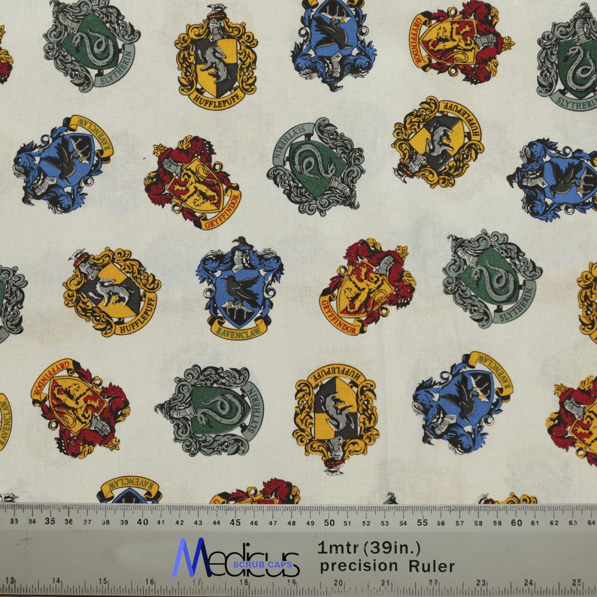 The Harry Potter Houses Scrub Cap by Medicus Scrub Caps features vibrant crests of Gryffindor (red), Slytherin (green), Hufflepuff (yellow), and Ravenclaw (blue) on this themed fabric, ideal for honoring healthcare heroes. A ruler design ensures precise measurements.