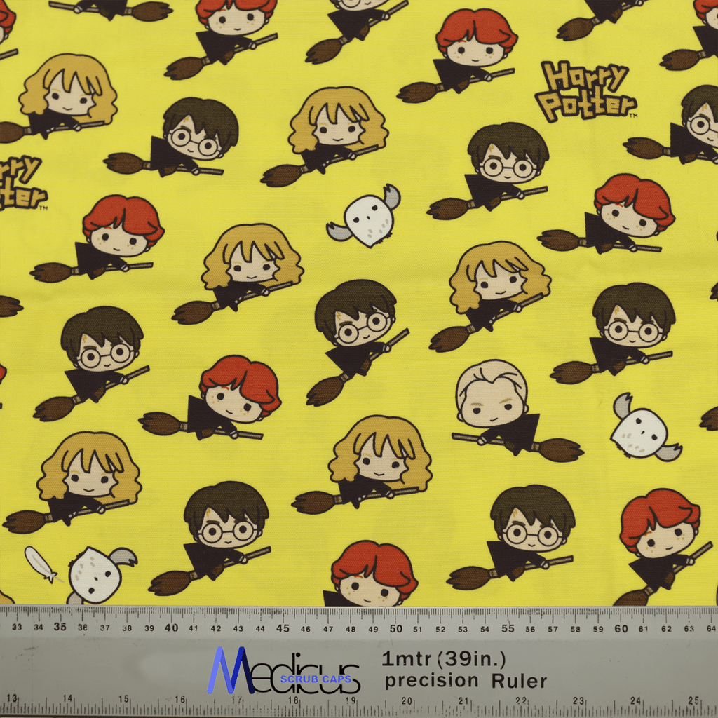 The Harry Potter Nimbus 2000 Scrub Cap by Medicus features yellow fabric with cartoon characters on broomsticks, including a red-haired boy, a girl with glasses, a blond boy, an owl, and repeating Harry Potter text and Nimbus 2000. Comes with measurements in inches and meters—ideal for crafting.