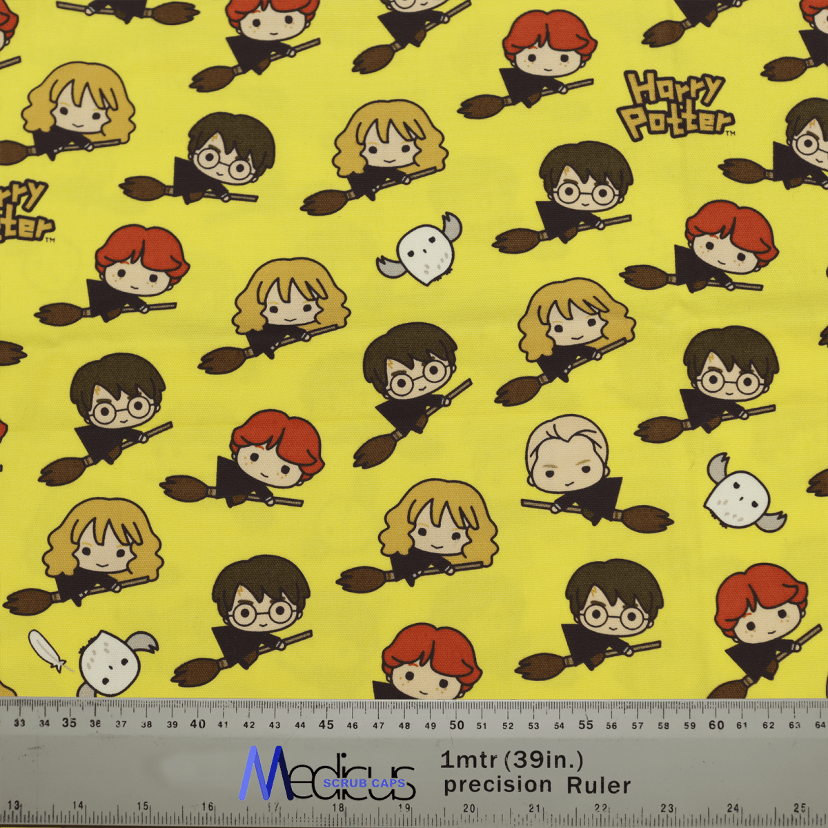 The Harry Potter Nimbus 2000 Scrub Cap by Medicus features yellow fabric with cartoon characters on broomsticks, including a red-haired boy, a girl with glasses, a blond boy, an owl, and repeating Harry Potter text and Nimbus 2000. Comes with measurements in inches and meters—ideal for crafting.