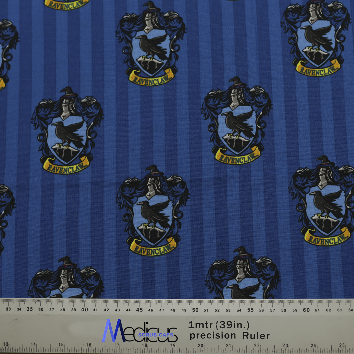 The Medicus Scrub Caps Harry Potter Ravenclaw Scrub Cap presents a blue fabric featuring a crest pattern with a bird and RAVENCLAW on a banner, set against vertical stripes. An eco-friendly ruler at the bottom measures in meters and inches. A must-have for every Harry Potter enthusiast!.